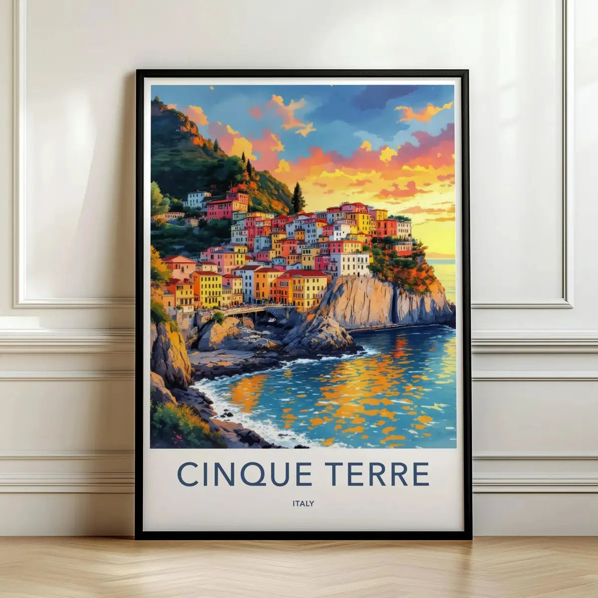 Framed travel poster of Cinque Terre's colorful cliffside village overlooking the sea leaning against a white wall.