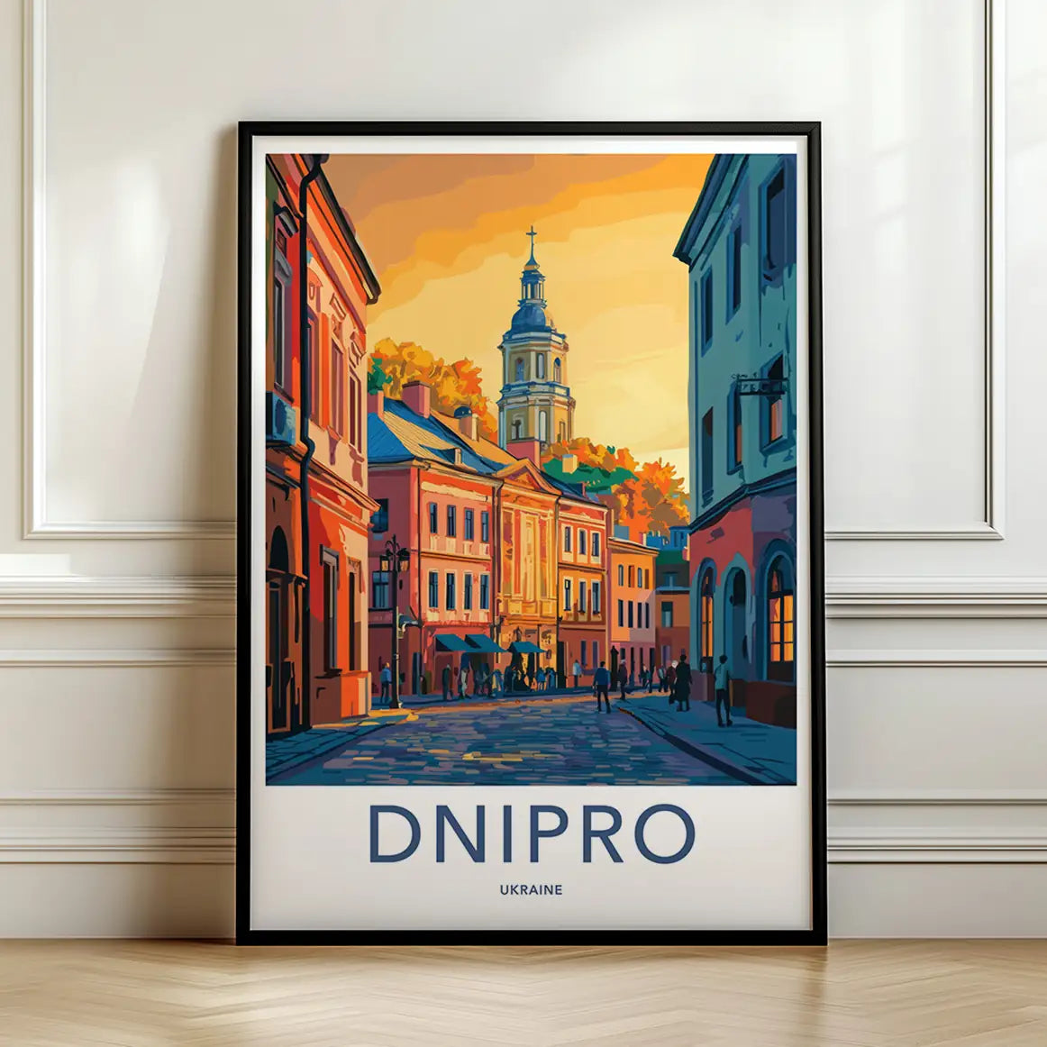 Framed travel poster of Dnipro's historic buildings and cobblestone streets in warm sunlight leaning against a white wall.