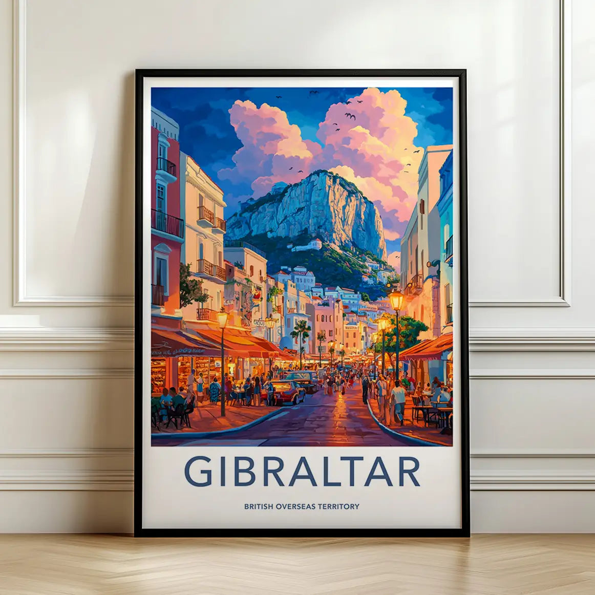 Framed travel poster of the Rock of Gibraltar over a vibrant street scene leaning against a white wall.