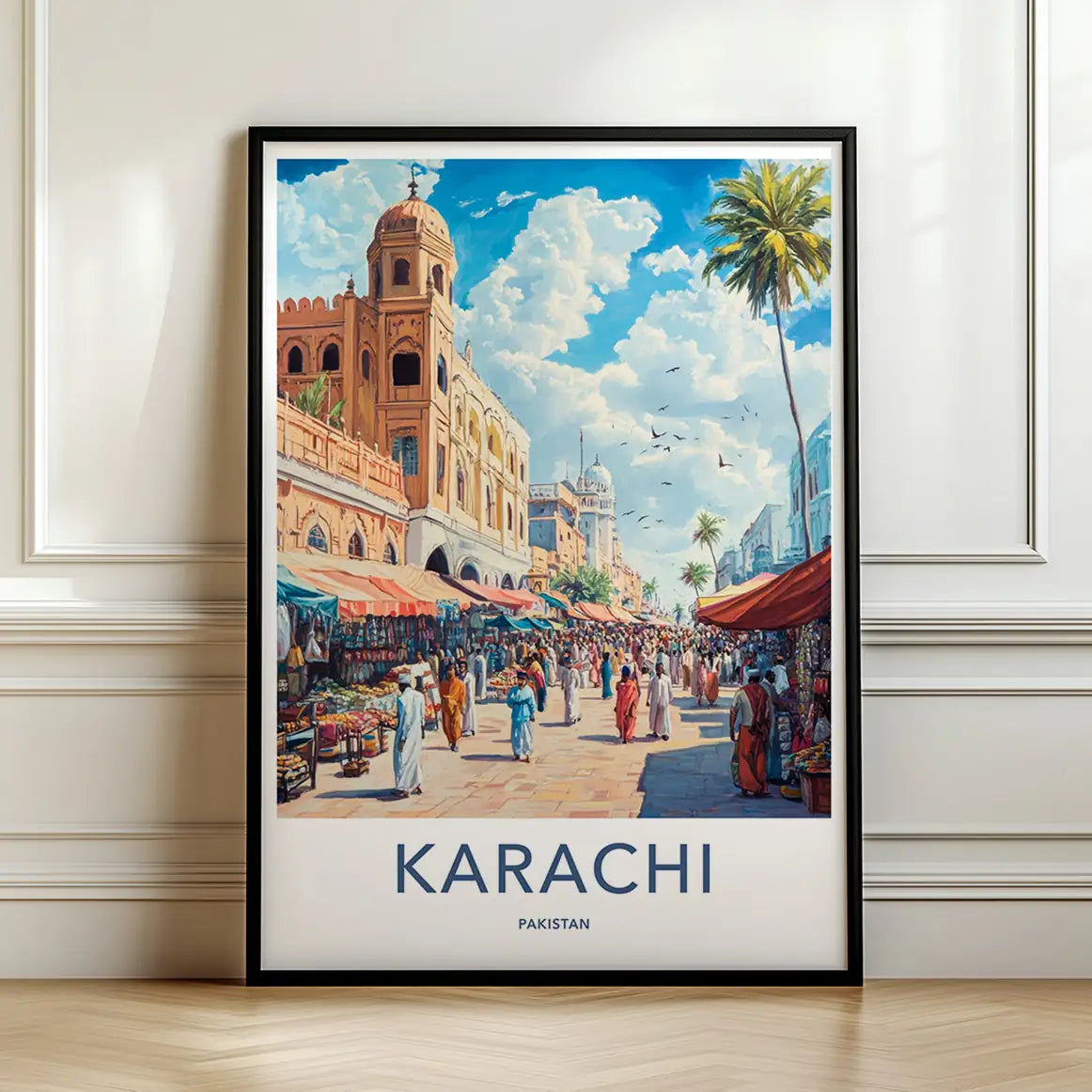 Framed travel poster of Karachi's historic street architecture and bustling crowds leaning against a white wall.