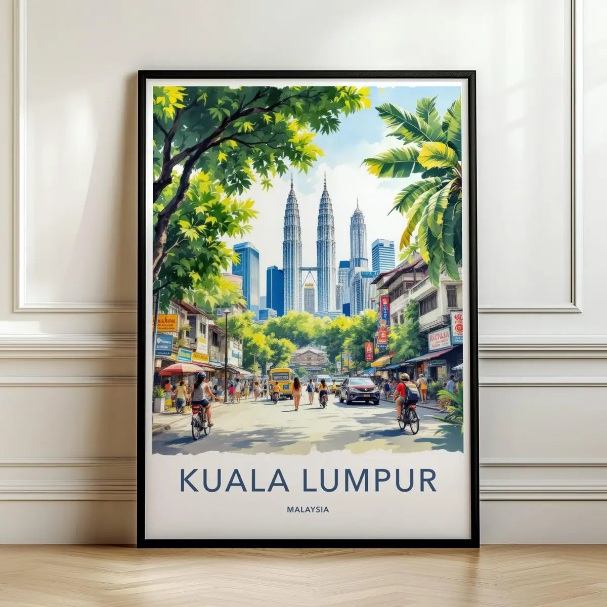 Framed travel poster of Kuala Lumpur's Petronas Towers rising above a busy street leaning against a white wall.