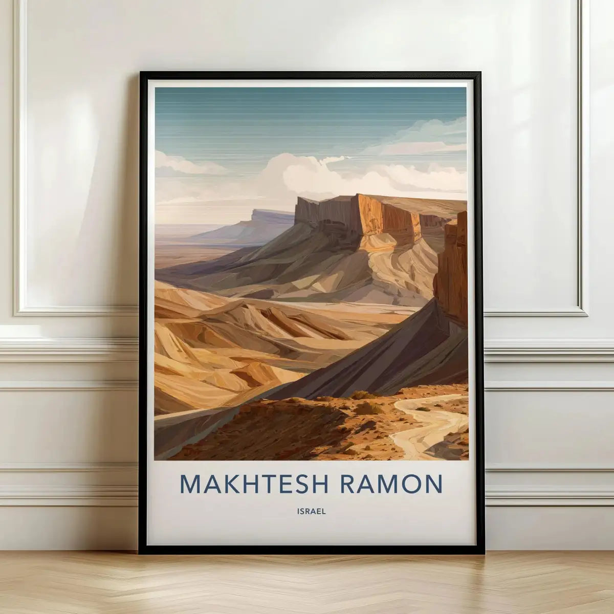 Framed travel poster of the Makhtesh Ramon desert crater with deep rocky canyons leaning against a white wall.