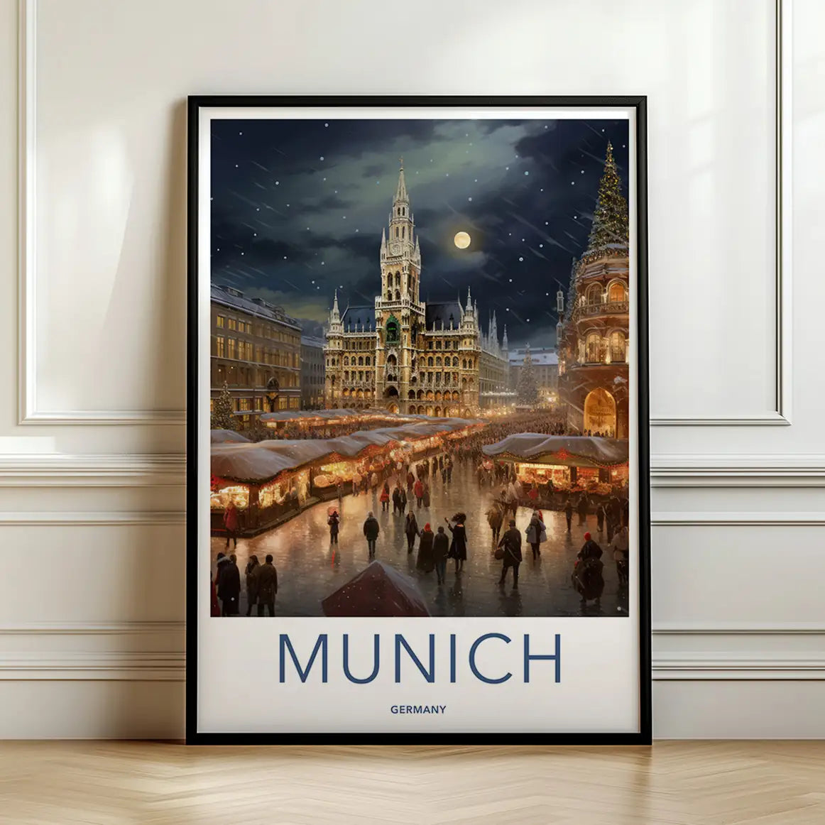 Framed travel poster of Munich's illuminated Marienplatz and city hall at night leaning against a white wall.