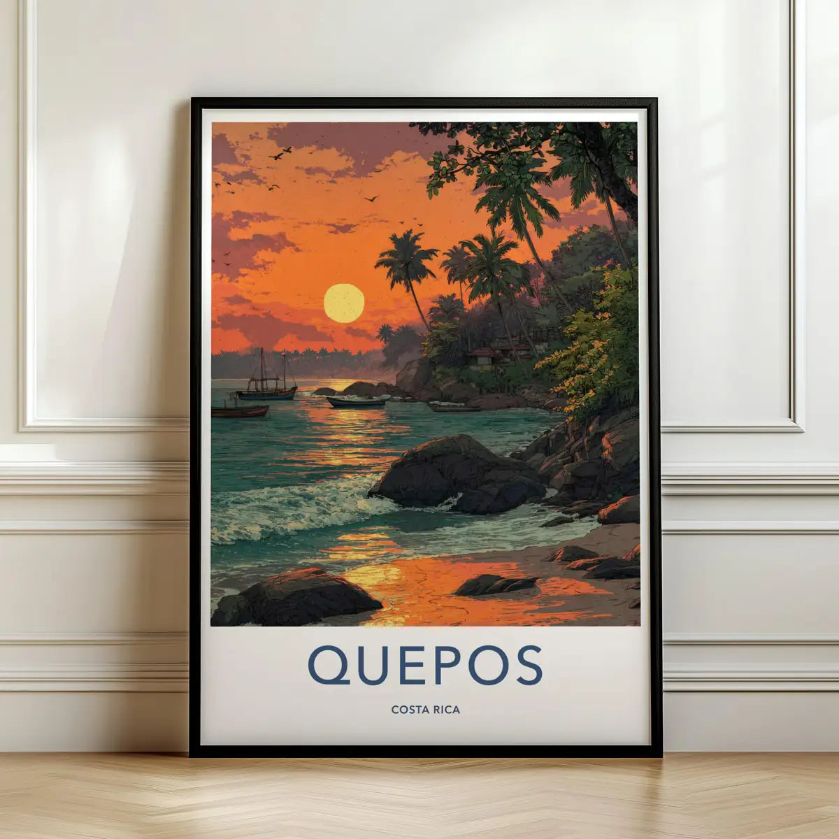 Framed travel poster of a tropical sunset over the rocky coastline and palm trees of Quepos leaning against a white wall.