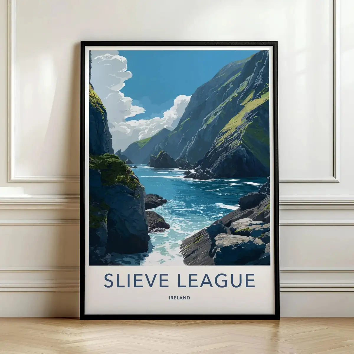 Framed travel poster of the steep green coastal cliffs of Slieve League meeting the ocean leaning against a white wall.