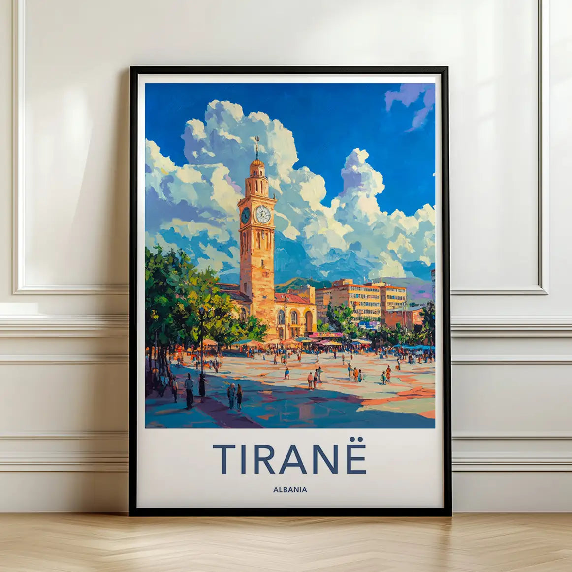 Framed travel poster of Tirane's historic clock tower and bustling city square leaning against a white wall.