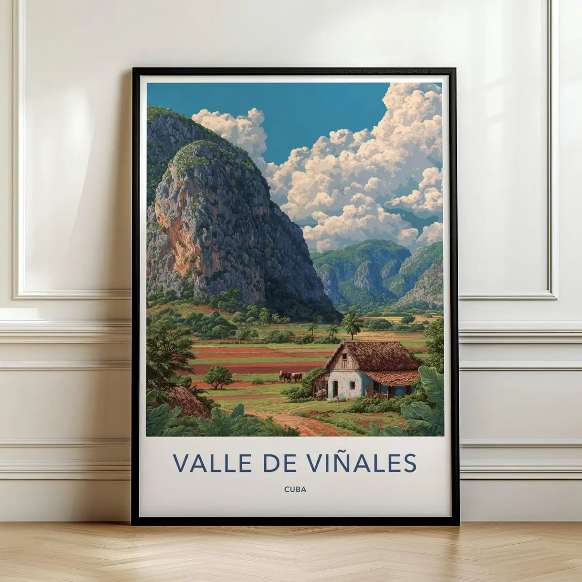 Framed travel poster of the steep green hills and a rural farmhouse in the Valle de Viñales leaning against a white wall.