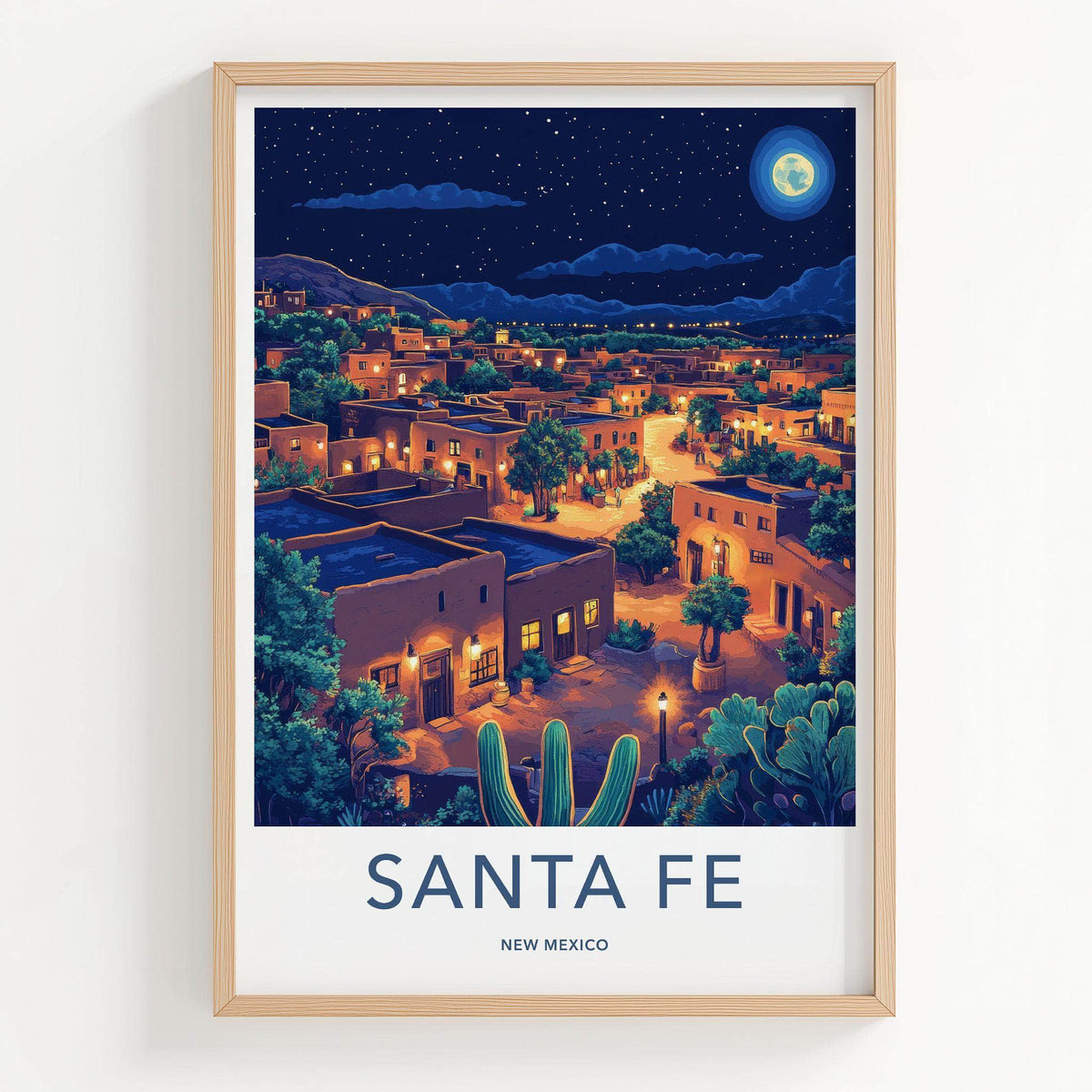 A framed art print featuring a stylized night illustration of Santa Fe, New Mexico, with adobe buildings, cacti, and a starry sky.
